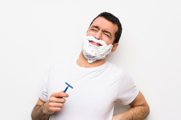 Man shaving his beard over isolated white background suffering from backache for having made an effort