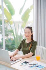 woman sitting at the table at home working using computer laptop with a happy face standing and smiling with a confident smile showing teeth