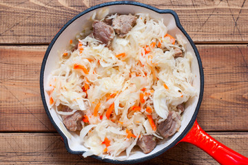 Step-by-step cooking sauerkraut stew with meat, step 4 - adding sauerkraut to meat and onions and stewing them together, top view, horizontal