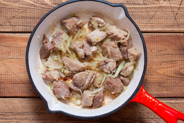 Step-by-step cooking of sauerkraut stew with meat, step 3 - frying chopped pork and chopped onions, top view, horizontal