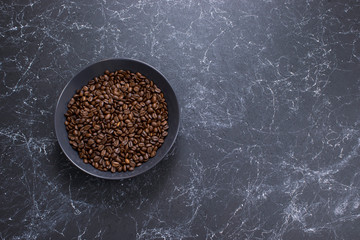 coffee beans in dark bowl cup on isolated dark textured background