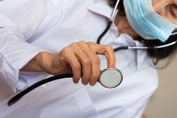 Close up hand female doctor in blue medical mask showing stethoscope for checkup auscultate...
