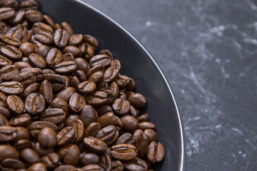 coffee beans in dark bowl cup on isolated dark textured background