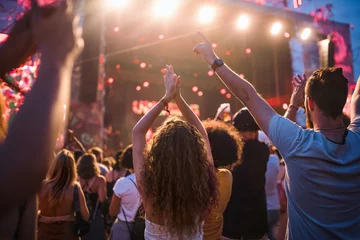 Fotobehang Rear view of group of young friends dancing at summer festival. © Halfpoint