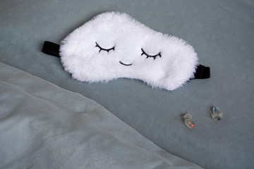 White cute sleep mask made of fluffy faux fur in a cloud shape with closed eyes embroidered on it...