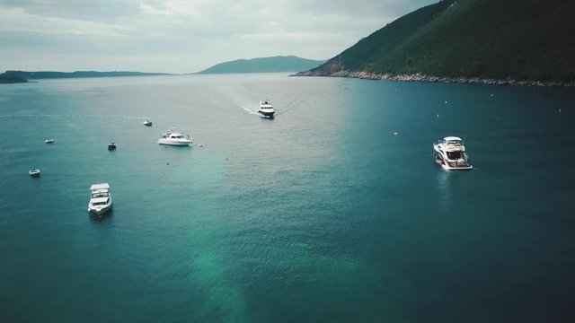 Yachts are sailing on the sea on the greenery mount island background