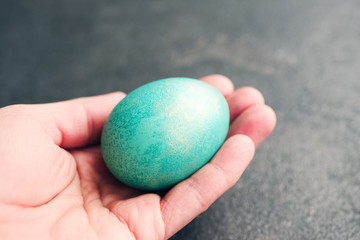 Women hands holding an easter blue egg, closeup