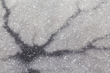 Dark cracks on thin ice. Background image. Dangerous ice. Thin spring ice.