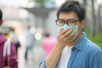 HandsomeMan wearing face mask protect filter against air pollution (PM2.5) or wear N95 mask. protect pollution, anti smog and viruses, Air pollution caused health problem. Global warming concept.