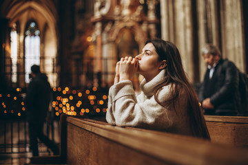 religion, faith, harmony and people concept: the parishioner of the church sits on a bench with her...