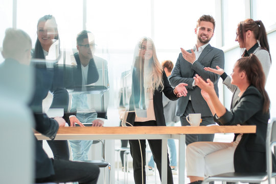 happy group of employees discussing something standing in the office.