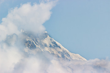 The top of the mountain is covered with ice and clouds.Clear Blue sky above. cold toning photo.