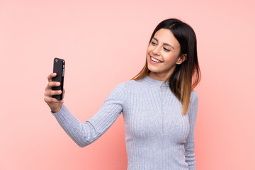 Woman over isolated pink background making a selfie