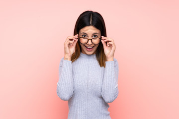 Woman over isolated pink background with glasses and surprised