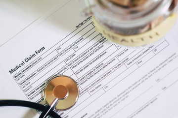 Stethoscope with coins lay on health insurance blank. Savings for medical issues 