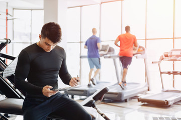 Obraz premium young guy trainer takes notes in the gym. personal trainer for sports.
