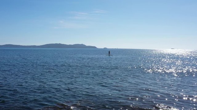 Male on a stand up paddle board aerial shot sunny day french riviera calm mediterranean sea France
