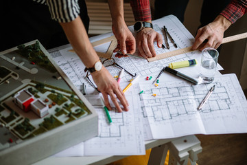 young experts, professional architects make high-rise building, complex construction model using drawings, blueprints. architecture, building, engineering concept © Roman