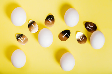 Easter concept. White eggs with golden letters on a yellow background