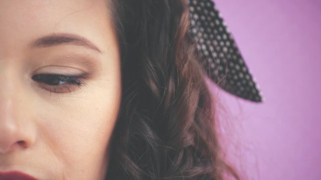 Half-side face of attractive young girl with kinky hair and black headband is looking dowm then at the camera.