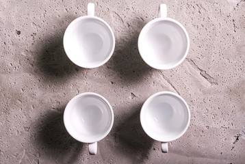 Four white empty coffee cups on a concrete board