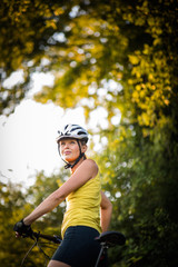 Naklejka premium Pretty, young woman biking on a mountain bike enjoying healthy active lifestyle outdoors in summer (shallow DOF)