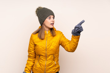 Woman with winter hat over isolated background pointing away