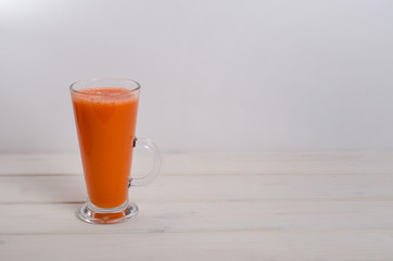 Glass of fresh carrot juice on a white wooden background. Healthy baby food