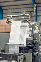 A industrial commercial envelope making machine, making paper envelopes for international distribution. Automated engineering machinery for mass production of paper envelopes.