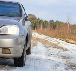 spring dirt road. beige car sedan.