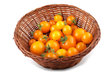 Yellow little tomatoes on wicker plate
