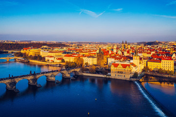 Obraz premium Aerial Prague panoramic drone view of the city of Prague at the Old Town Square, Czechia. Prague Old Town pier architecture and Charles Bridge over Vltava river in Prague at sunset, Czech Republic.