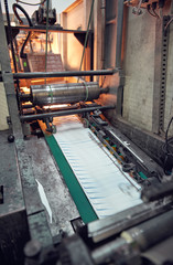 A industrial commercial envelope making machine, making paper envelopes for international distribution. Automated engineering machinery for mass production of paper envelopes.
