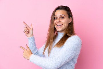 Teenager girl with blue sweater over isolated pink background pointing finger to the side