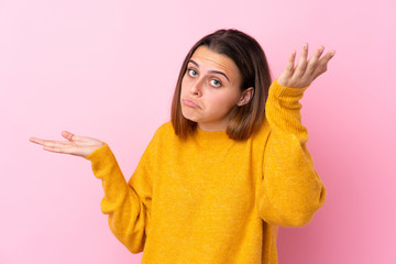 Teenager girl with yellow sweater over isolated pink background making doubts gesture