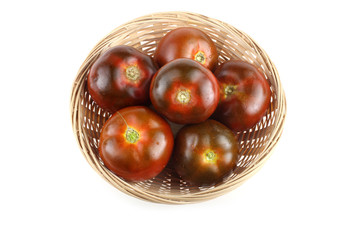 Dark tomatoes on wicker plate