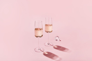 Sparkling wine glasses on colored pink background. Champagne glasses with sharp shadows. Modern, stylish color concept.
