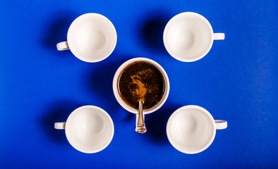 Obraz na płótnie Canvas Four empty cups and one cup with coffee on a dark blue background