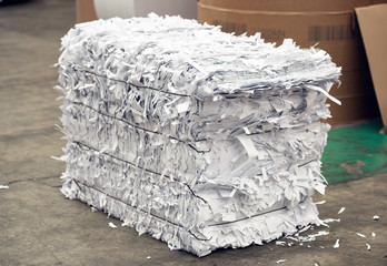 A paper recycling factory plant shredding producing waste paper into square bails, ready to be...