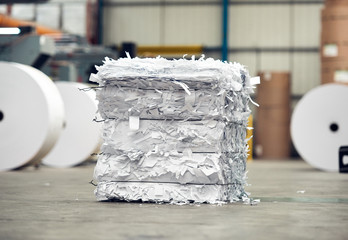A paper recycling factory plant shredding producing waste paper into square bails, ready to be...