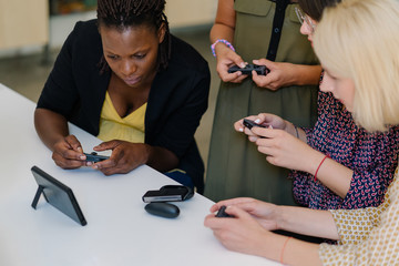 Focused multiethnic game developer women team testing their new product console games