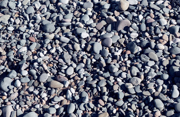 A overhead view of grey and blue rustic beach pebbles on a stoney beach setting. Rocky Coast line textures and repeat patterns. Natures uniformed shapes, round smooth beach stones.
