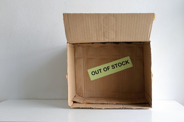 Closeup OUT OF STOCK sign inside of an empty carton. People hoarding supplies such as face mask, hand sanitizer, food, toilet paper etc. as a result of covid-19 outbreak    © evergreentree