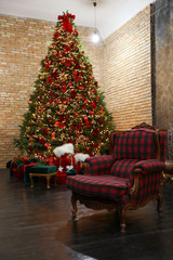 Festive room interior with stylish armchair and beautiful Christmas tree