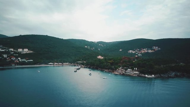 Top view on the island with mount lands and small towns, near coastline there are marina with yachts, surrounded the sea