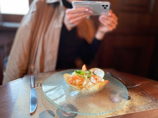 Obraz na płótnie Canvas girl photographs a restaurant dish on a smartphone