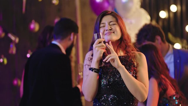 In front of the camera smiling and feeling happy beautiful lady enjoying the time she dancing at glamorous party background other people enjoying the evening