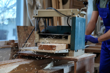Professional carpenter working with grinding machine in shop, closeup