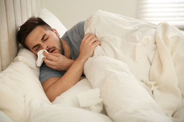 Sick young man in bed at home. Influenza virus