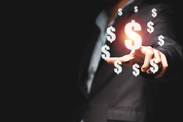 Businessman hand point to USD dollar sign with sunlight and black background. Dollar money is and and number one of  exchange currency in the world.